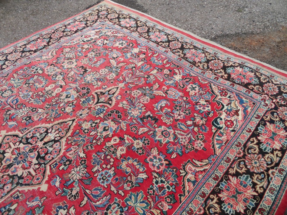 A large hand-knotted Sarouk Persian carpet featuring a dense red floral ground, central medallion, and elaborate dark borders. View XIII