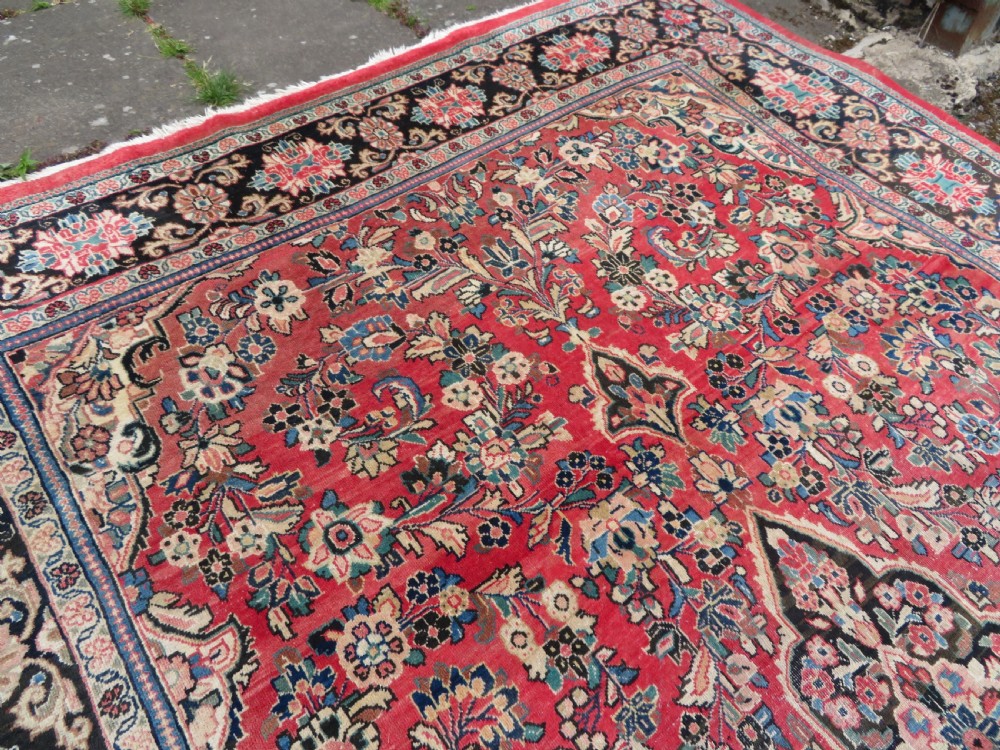 A large hand-knotted Sarouk Persian carpet featuring a dense red floral ground, central medallion, and elaborate dark borders. View XIV