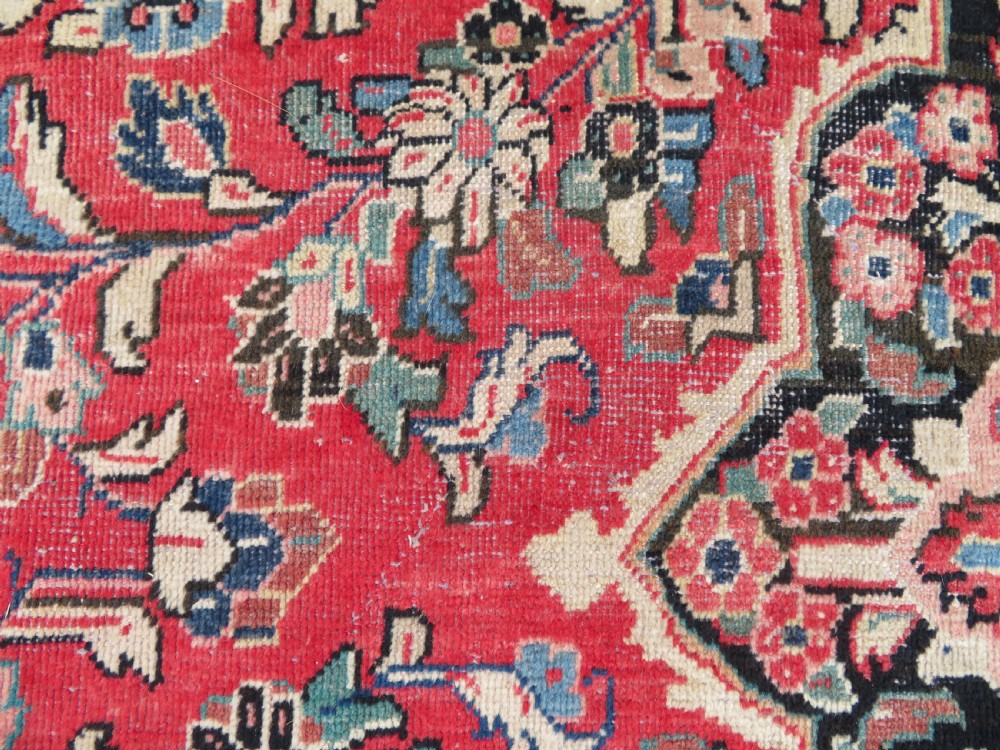 A large hand-knotted Sarouk Persian carpet featuring a dense red floral ground, central medallion, and elaborate dark borders. View XV