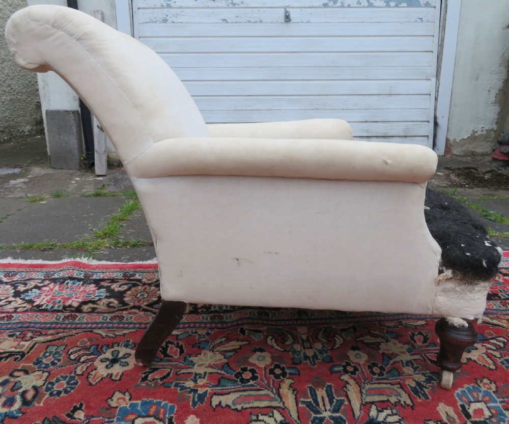 A Howard style low easy chair frame with exposed horsehair seat filling, cream calico back, and turned front wooden legs on ceramic castors. View II