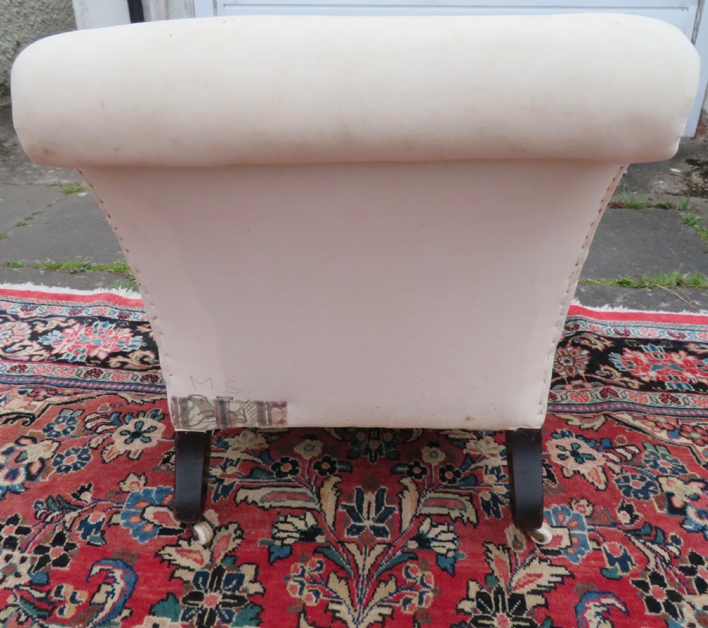 A Howard style low easy chair frame with exposed horsehair seat filling, cream calico back, and turned front wooden legs on ceramic castors. View III