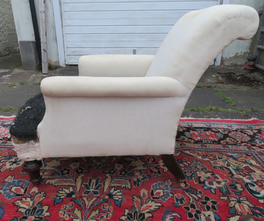 A Howard style low easy chair frame with exposed horsehair seat filling, cream calico back, and turned front wooden legs on ceramic castors. View IV