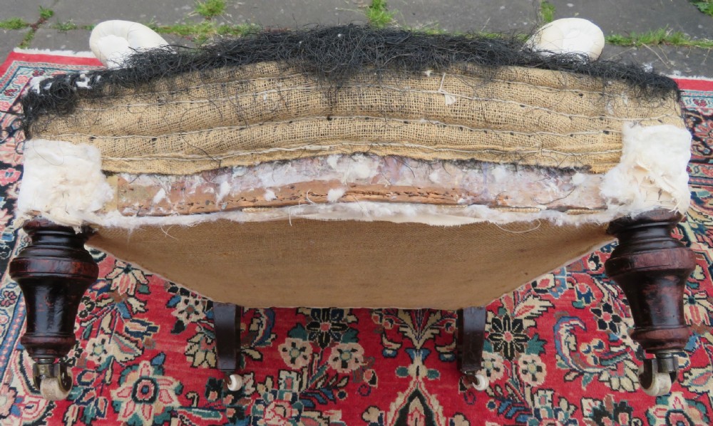 A Howard style low easy chair frame with exposed horsehair seat filling, cream calico back, and turned front wooden legs on ceramic castors. View VII