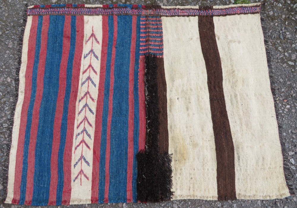 An antique flatweave Kurdish Tasheh wheat sack featuring vertical blue, red, cream, and brown stripes alongside a woven chevron motif.