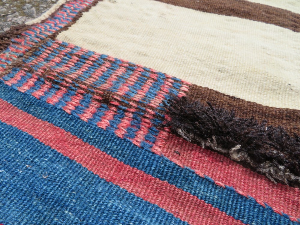 An antique flatweave Kurdish Tasheh wheat sack featuring vertical blue, red, cream, and brown stripes alongside a woven chevron motif. View III
