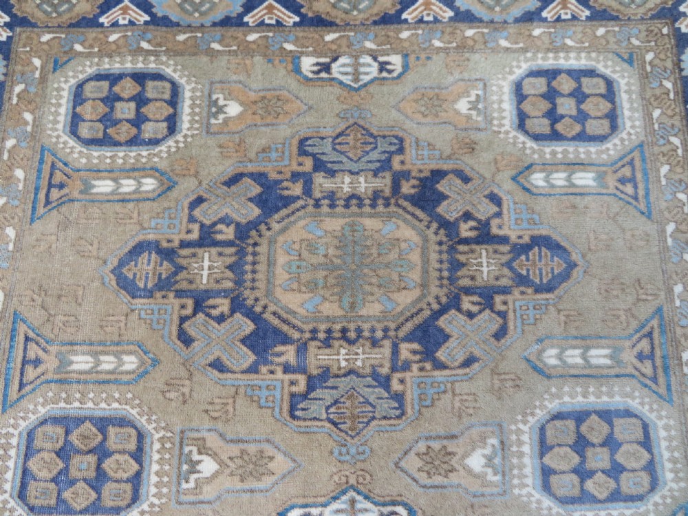 A hand-knotted North Persian Ardabil wool rug featuring three central geometric medallions in blue, cream, and beige on a neutral field with patterned borders. View III