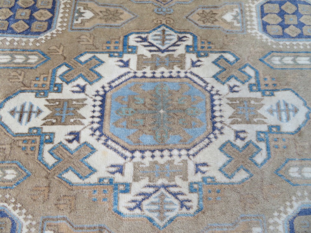 A hand-knotted North Persian Ardabil wool rug featuring three central geometric medallions in blue, cream, and beige on a neutral field with patterned borders. View IV