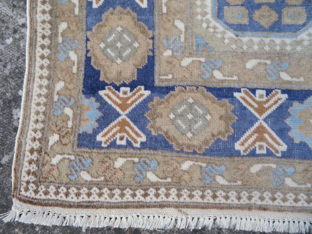 A hand-knotted North Persian Ardabil wool rug featuring three central geometric medallions in blue, cream, and beige on a neutral field with patterned borders. View V