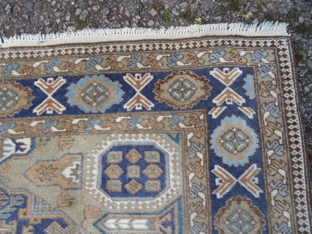 A hand-knotted North Persian Ardabil wool rug featuring three central geometric medallions in blue, cream, and beige on a neutral field with patterned borders. View VI