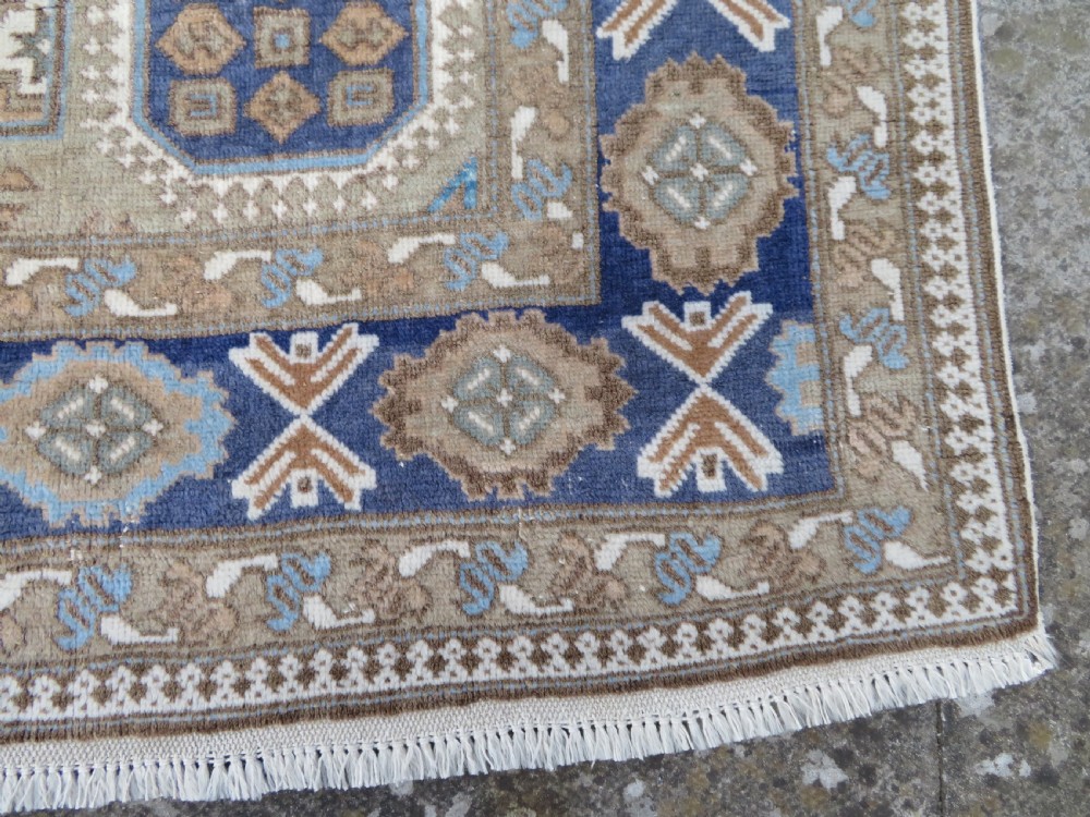 A hand-knotted North Persian Ardabil wool rug featuring three central geometric medallions in blue, cream, and beige on a neutral field with patterned borders. View VII