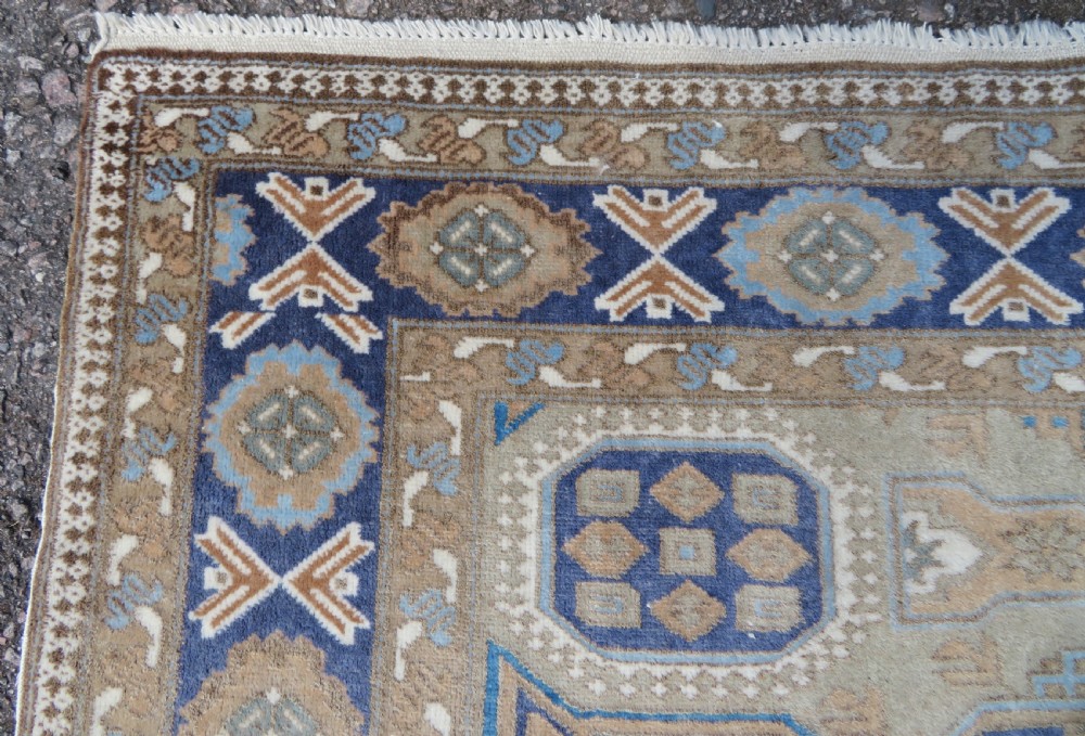 A hand-knotted North Persian Ardabil wool rug featuring three central geometric medallions in blue, cream, and beige on a neutral field with patterned borders. View VIII