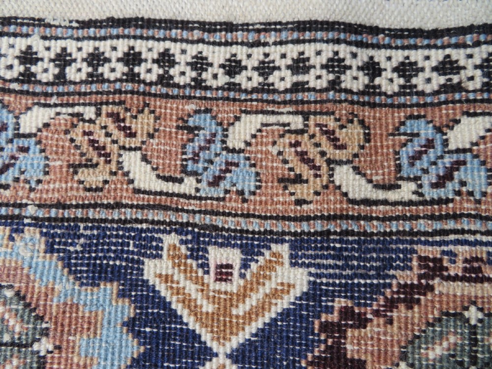 A hand-knotted North Persian Ardabil wool rug featuring three central geometric medallions in blue, cream, and beige on a neutral field with patterned borders. View XV