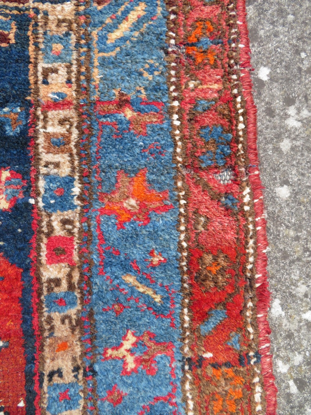 An antique hand-knotted Persian Sarab rug featuring a central dark blue geometric medallion on a red patterned field with light blue borders. View VIII