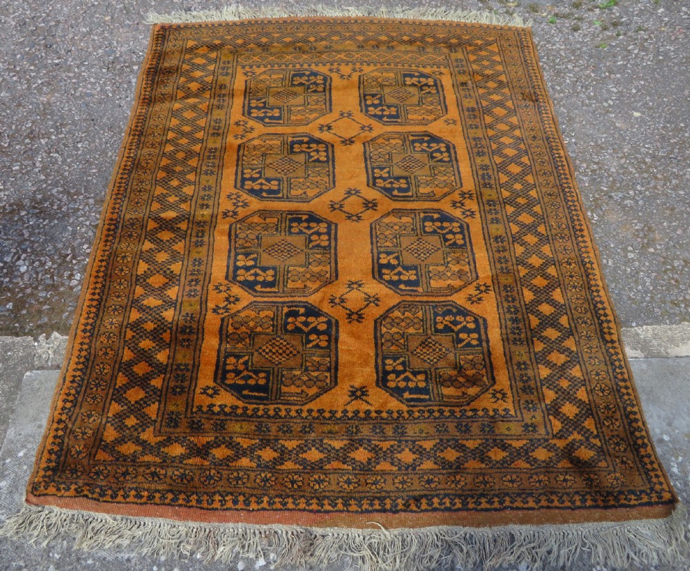 A rectangular hand-knotted Afghan wool rug with dark blue octagonal gul motifs set against a rich gold field with geometric borders. View III