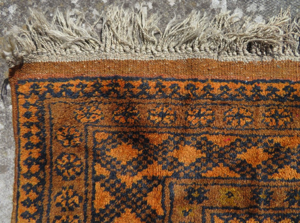 A rectangular hand-knotted Afghan wool rug with dark blue octagonal gul motifs set against a rich gold field with geometric borders. View V