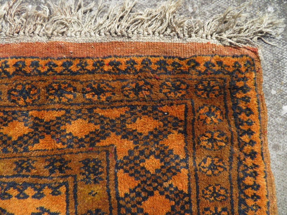 A rectangular hand-knotted Afghan wool rug with dark blue octagonal gul motifs set against a rich gold field with geometric borders. View VII