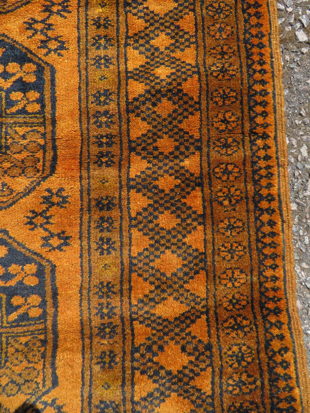 A rectangular hand-knotted Afghan wool rug with dark blue octagonal gul motifs set against a rich gold field with geometric borders. View VIII