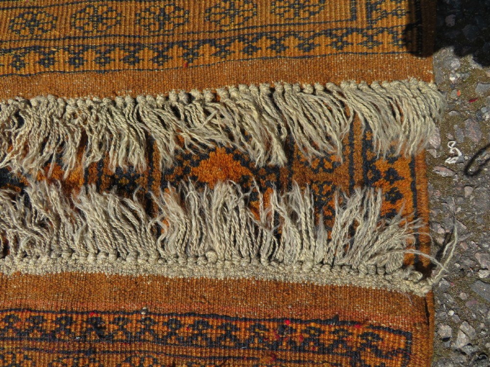 A rectangular hand-knotted Afghan wool rug with dark blue octagonal gul motifs set against a rich gold field with geometric borders. View XII