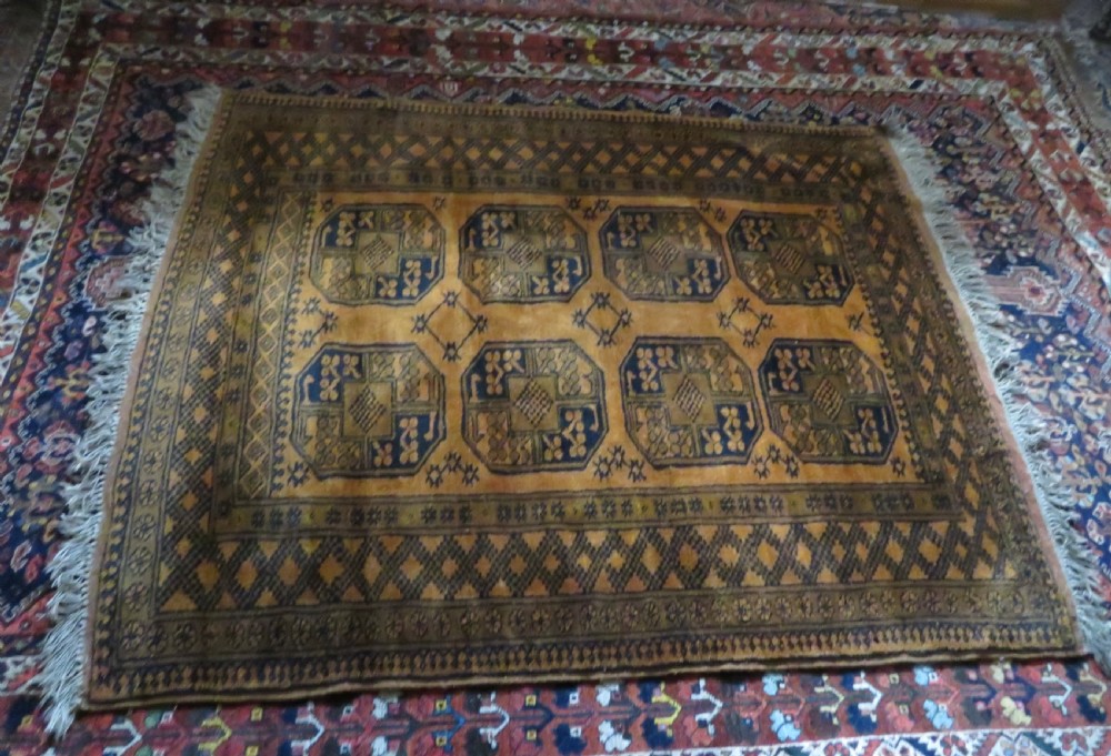 A rectangular hand-knotted Afghan wool rug with dark blue octagonal gul motifs set against a rich gold field with geometric borders. View XV