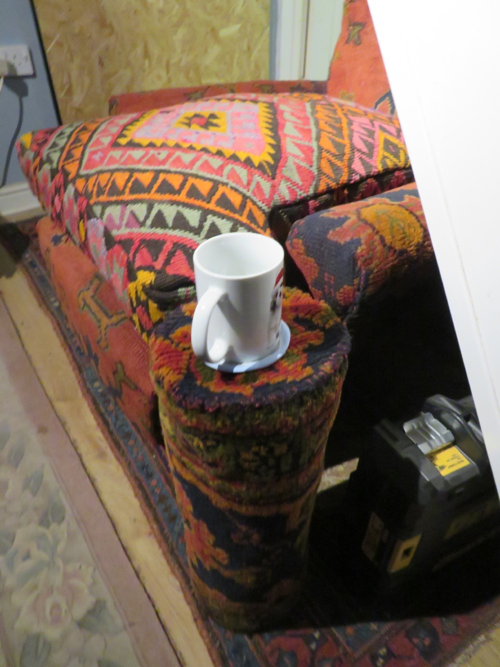 A low-slung, deep-seated Howard and Sons club armchair upholstered in a terracotta red and multi-coloured Ushak carpet pattern with turned legs on brass castors. View XXVI