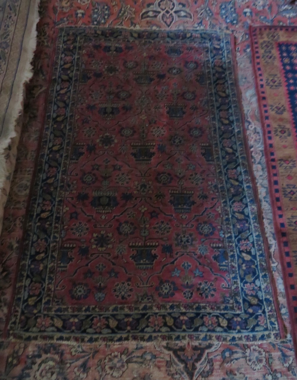 An antique West Persian Sarouk hand-knotted wool rug featuring a rose pink field adorned with floral vase motifs and a navy blue floral border. View III