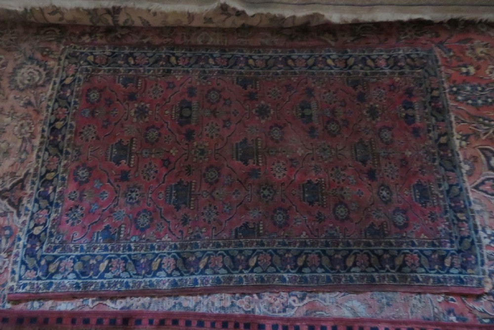 An antique West Persian Sarouk hand-knotted wool rug featuring a rose pink field adorned with floral vase motifs and a navy blue floral border. View V
