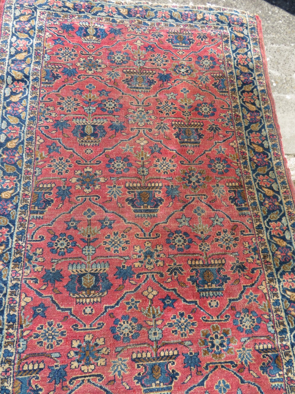 An antique West Persian Sarouk hand-knotted wool rug featuring a rose pink field adorned with floral vase motifs and a navy blue floral border. View VI
