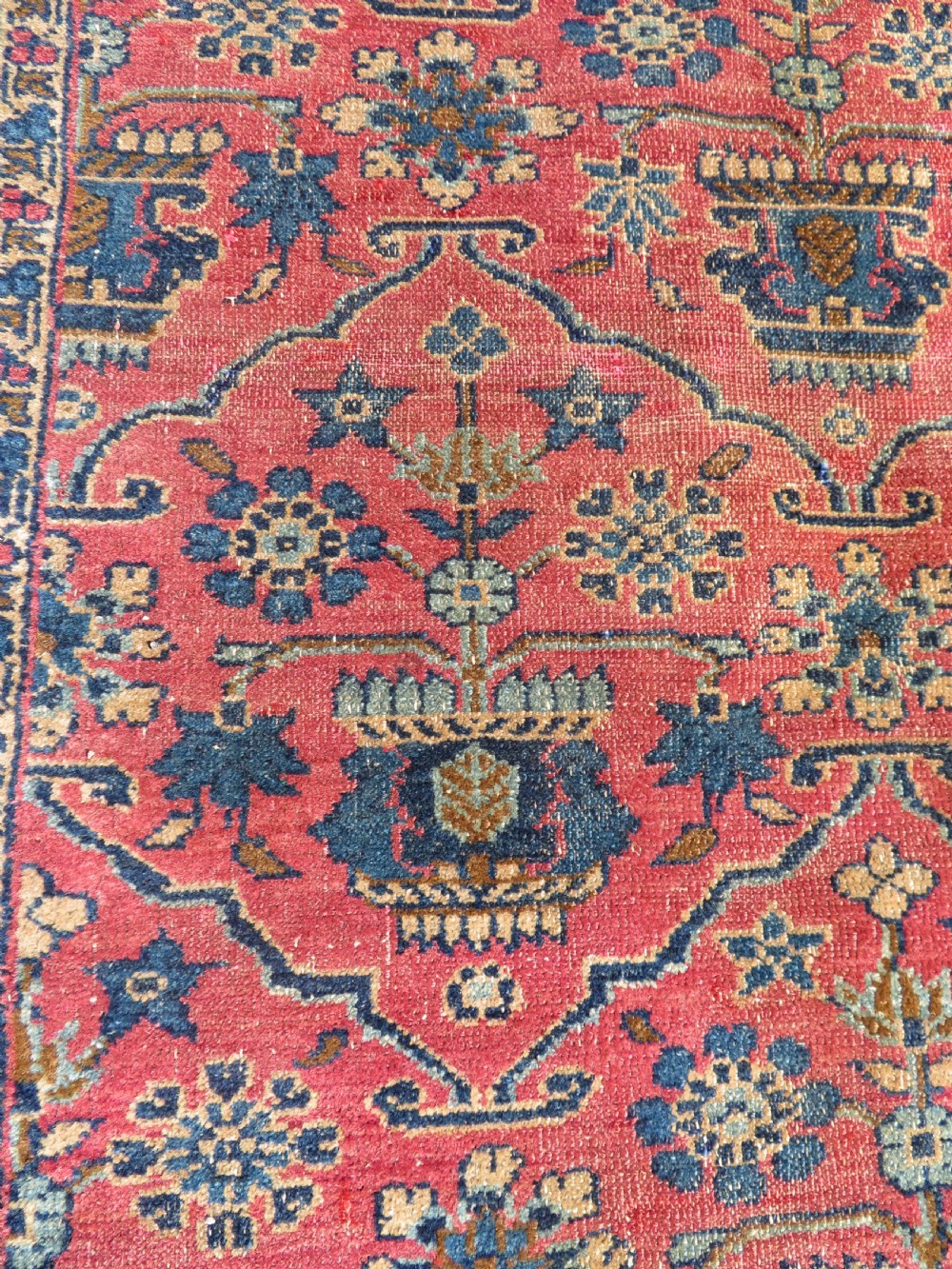 An antique West Persian Sarouk hand-knotted wool rug featuring a rose pink field adorned with floral vase motifs and a navy blue floral border. View VIII