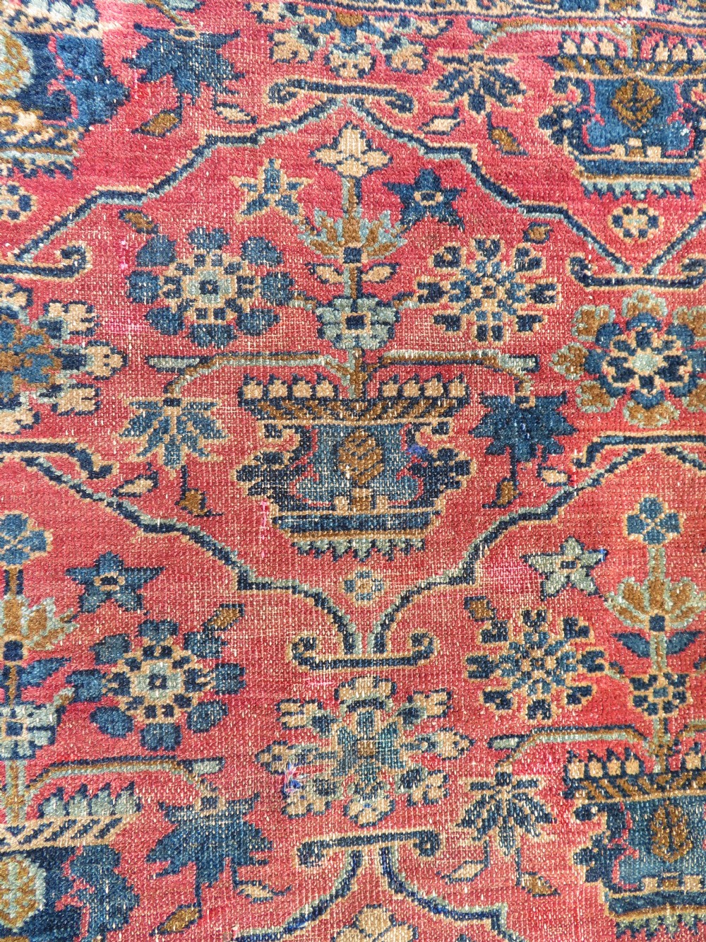 An antique West Persian Sarouk hand-knotted wool rug featuring a rose pink field adorned with floral vase motifs and a navy blue floral border. View X
