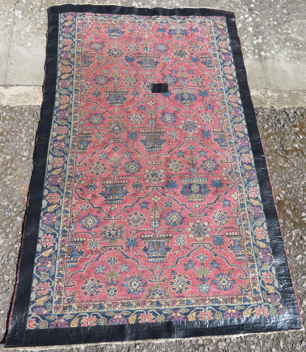 An antique West Persian Sarouk hand-knotted wool rug featuring a rose pink field adorned with floral vase motifs and a navy blue floral border. View XII