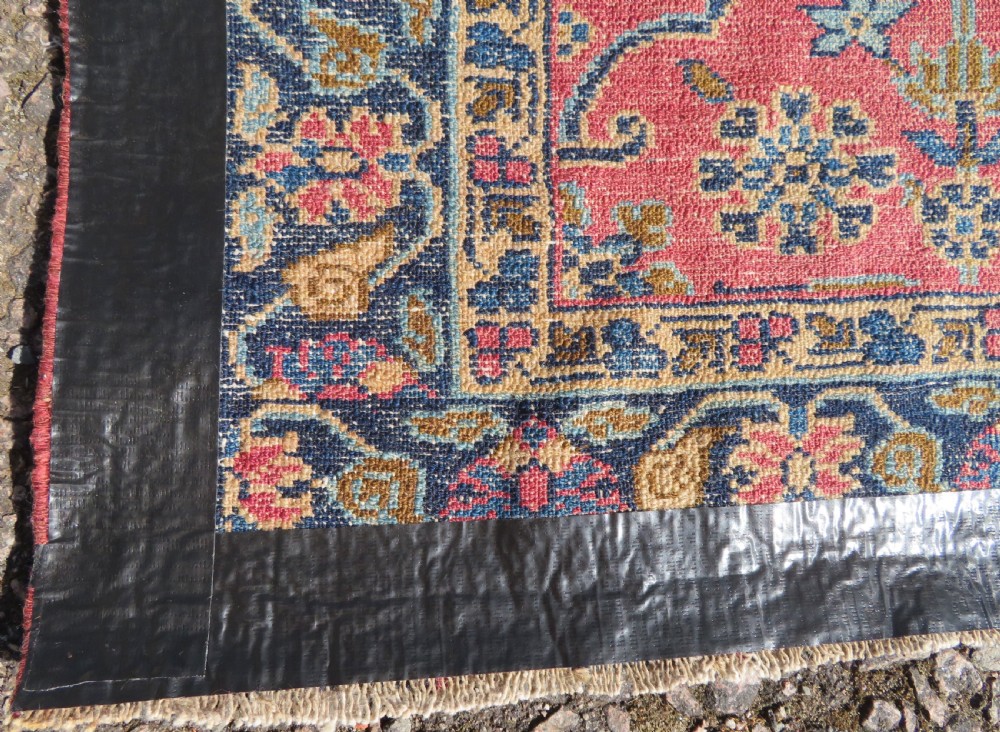 An antique West Persian Sarouk hand-knotted wool rug featuring a rose pink field adorned with floral vase motifs and a navy blue floral border. View XIII