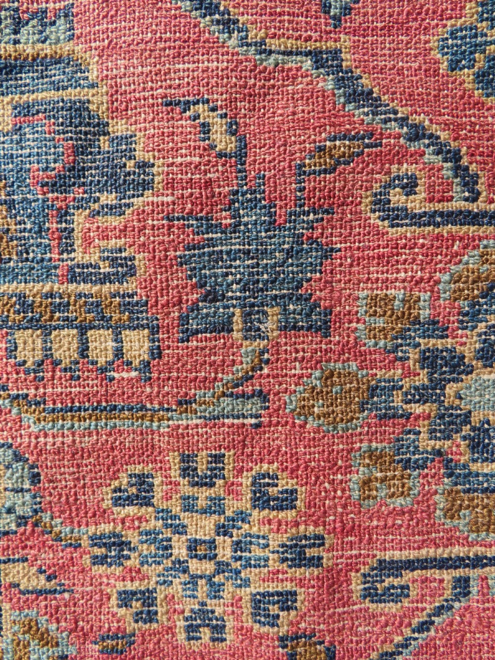 An antique West Persian Sarouk hand-knotted wool rug featuring a rose pink field adorned with floral vase motifs and a navy blue floral border. View XV