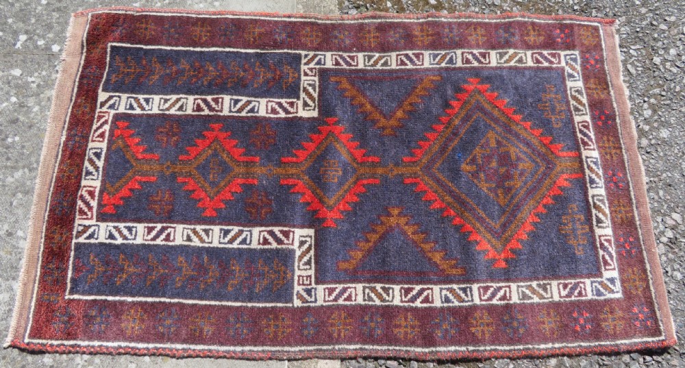 A hand-knotted antique Persian Baluch prayer rug with geometric diamond motifs in rust red and brown against a dark blue central field. View II