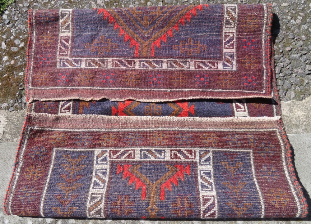 A hand-knotted antique Persian Baluch prayer rug with geometric diamond motifs in rust red and brown against a dark blue central field. View VIII