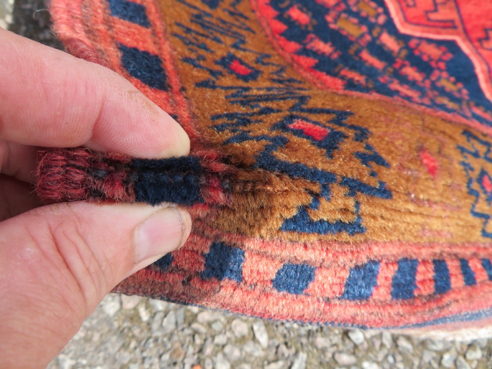 A handwoven Turkish wool rug featuring three central red star medallions on a dark navy blue field with geometric borders in ochre brown. View III
