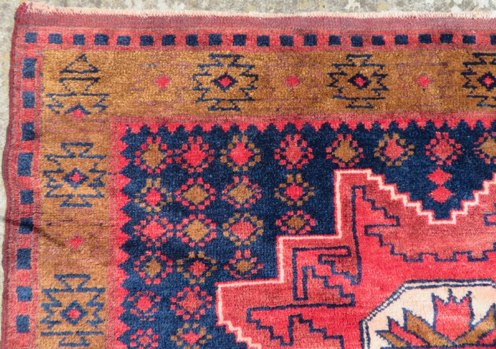 A handwoven Turkish wool rug featuring three central red star medallions on a dark navy blue field with geometric borders in ochre brown. View VI