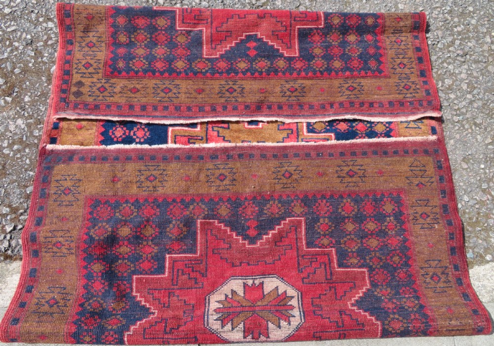 A handwoven Turkish wool rug featuring three central red star medallions on a dark navy blue field with geometric borders in ochre brown. View IX