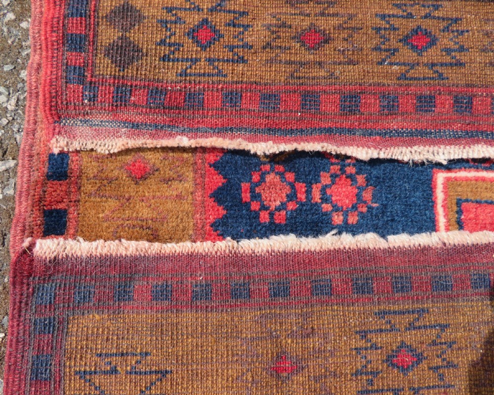 A handwoven Turkish wool rug featuring three central red star medallions on a dark navy blue field with geometric borders in ochre brown. View X
