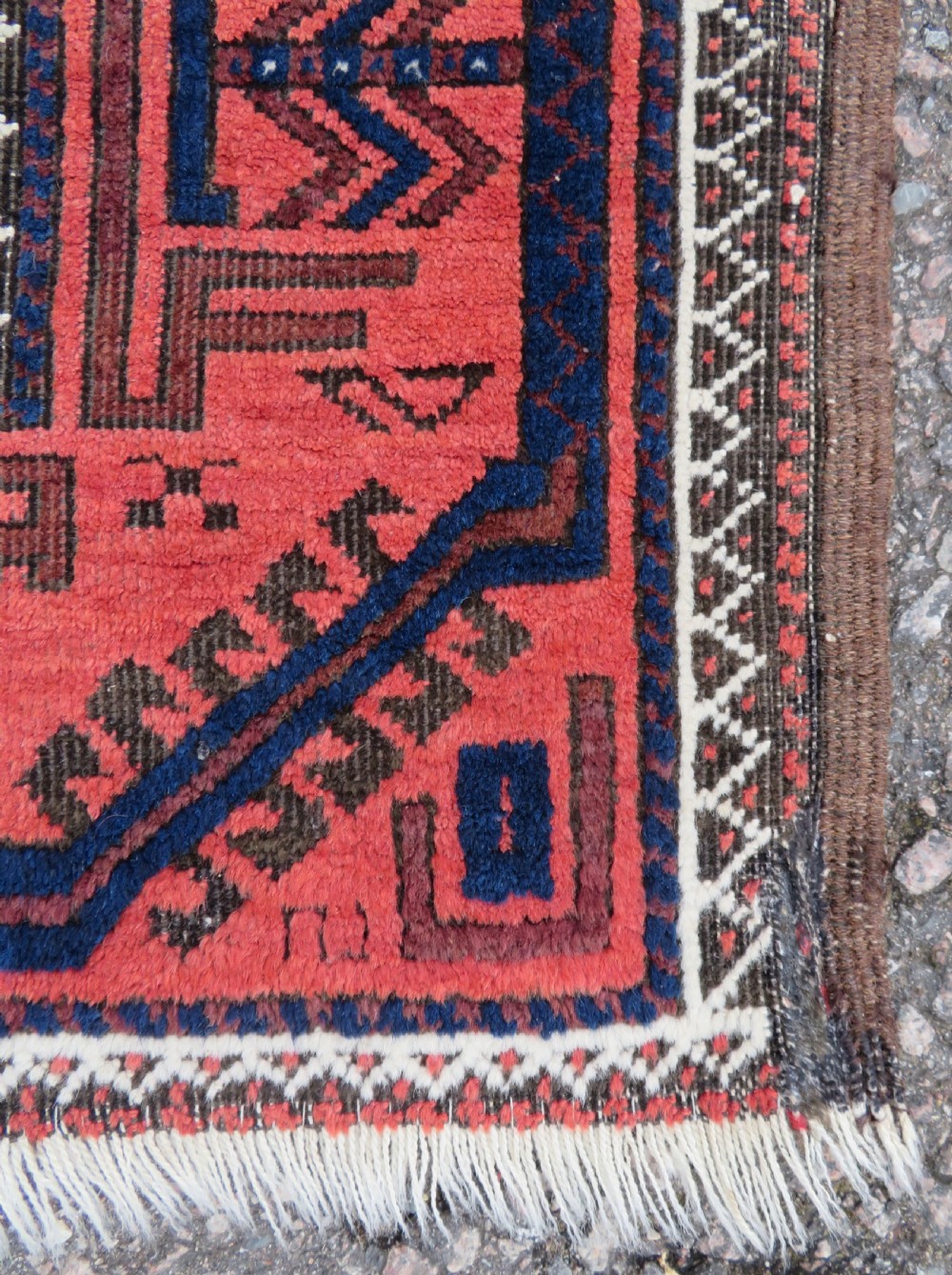 An antique hand-knotted Baluch wool rug featuring repeating geometric diamond motifs in deep red, navy blue, and brown tones with fringed ends. View VIII