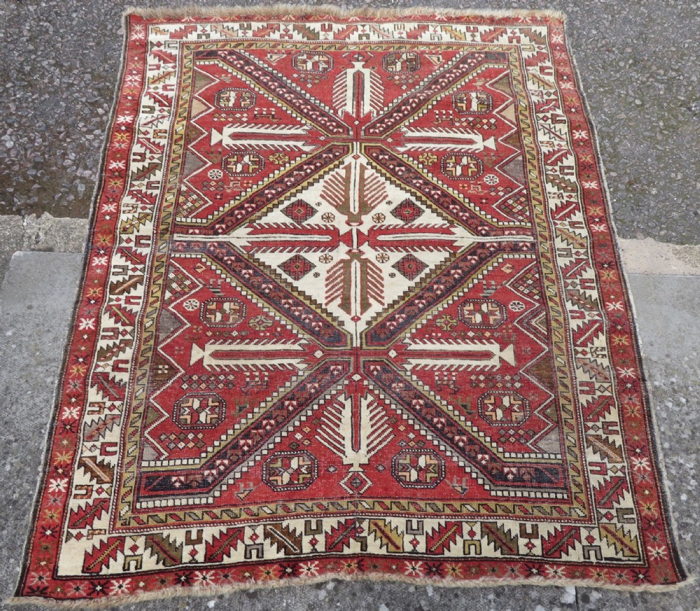 An antique hand-knotted Shirvan wool rug featuring a central diamond medallion, geometric motifs, and detailed borders in shades of red, cream, and brown. View II