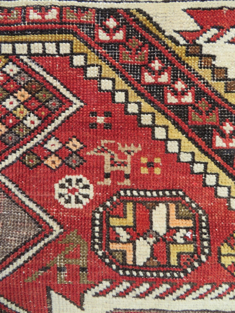An antique hand-knotted Shirvan wool rug featuring a central diamond medallion, geometric motifs, and detailed borders in shades of red, cream, and brown. View III