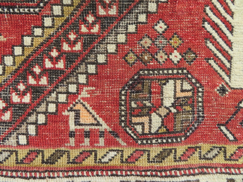 An antique hand-knotted Shirvan wool rug featuring a central diamond medallion, geometric motifs, and detailed borders in shades of red, cream, and brown. View IV
