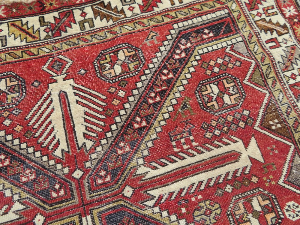 An antique hand-knotted Shirvan wool rug featuring a central diamond medallion, geometric motifs, and detailed borders in shades of red, cream, and brown. View VI