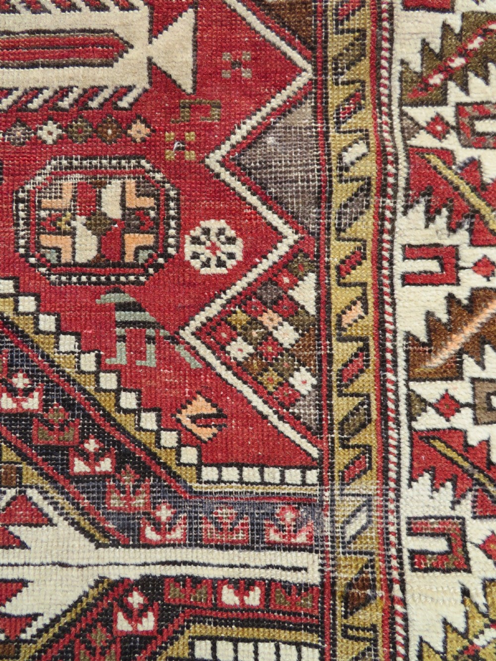 An antique hand-knotted Shirvan wool rug featuring a central diamond medallion, geometric motifs, and detailed borders in shades of red, cream, and brown. View VII