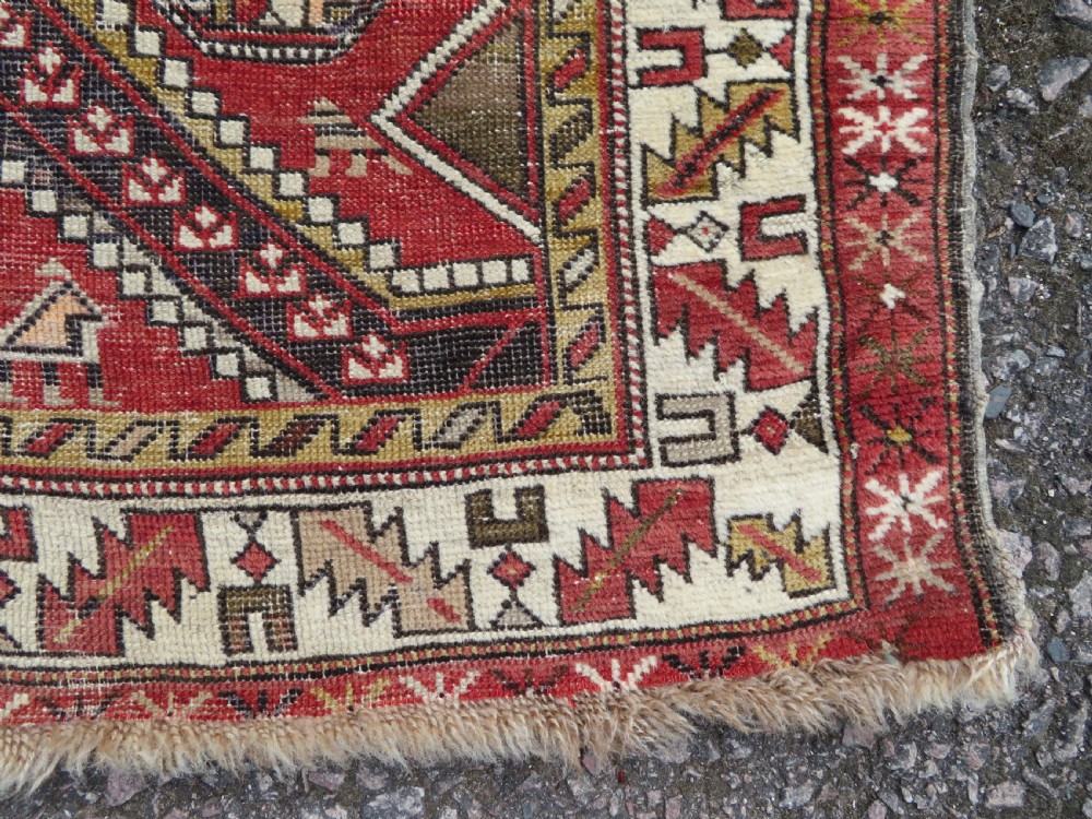An antique hand-knotted Shirvan wool rug featuring a central diamond medallion, geometric motifs, and detailed borders in shades of red, cream, and brown. View VIII