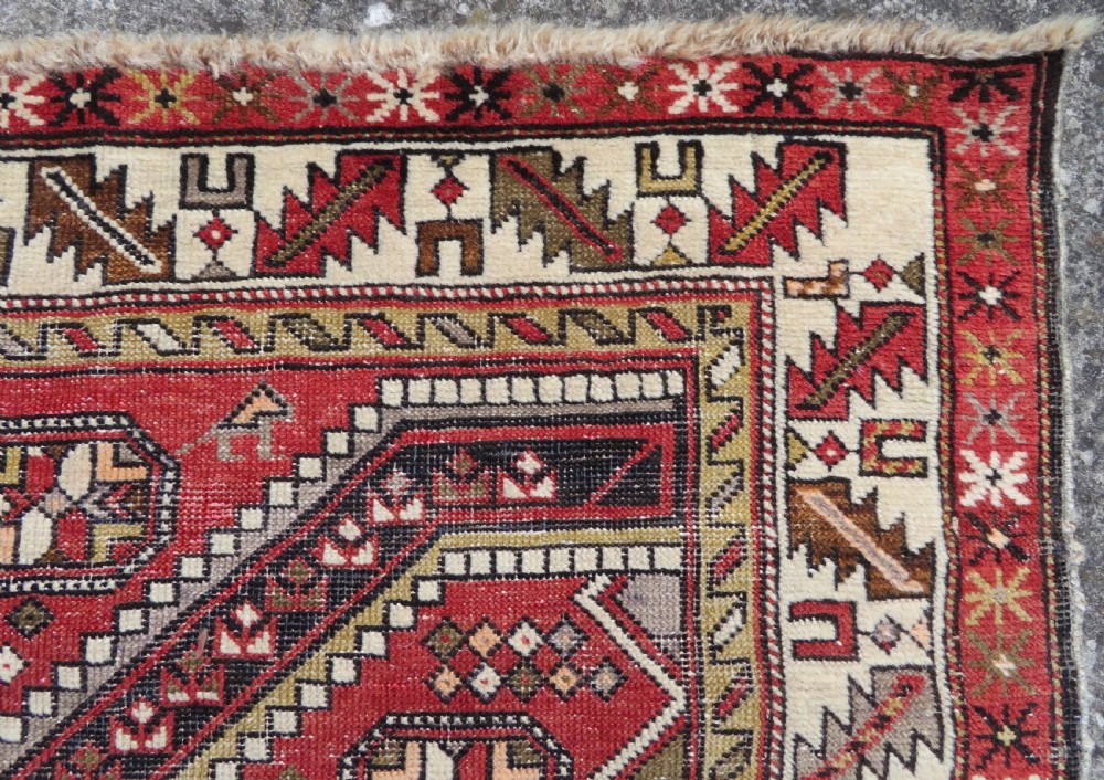An antique hand-knotted Shirvan wool rug featuring a central diamond medallion, geometric motifs, and detailed borders in shades of red, cream, and brown. View XI