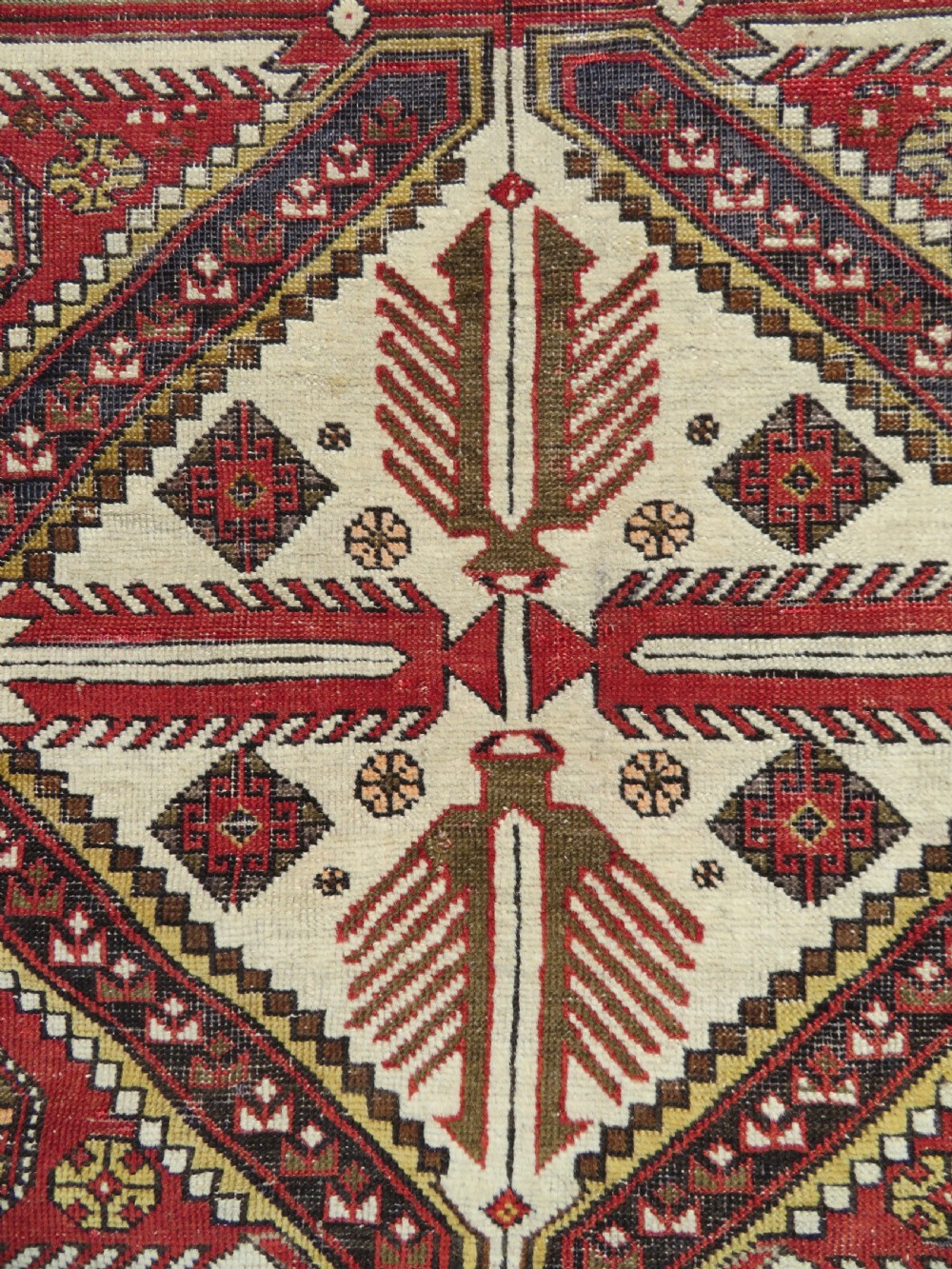 An antique hand-knotted Shirvan wool rug featuring a central diamond medallion, geometric motifs, and detailed borders in shades of red, cream, and brown. View XIII