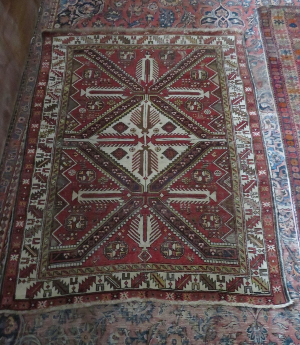 An antique hand-knotted Shirvan wool rug featuring a central diamond medallion, geometric motifs, and detailed borders in shades of red, cream, and brown. View XXI