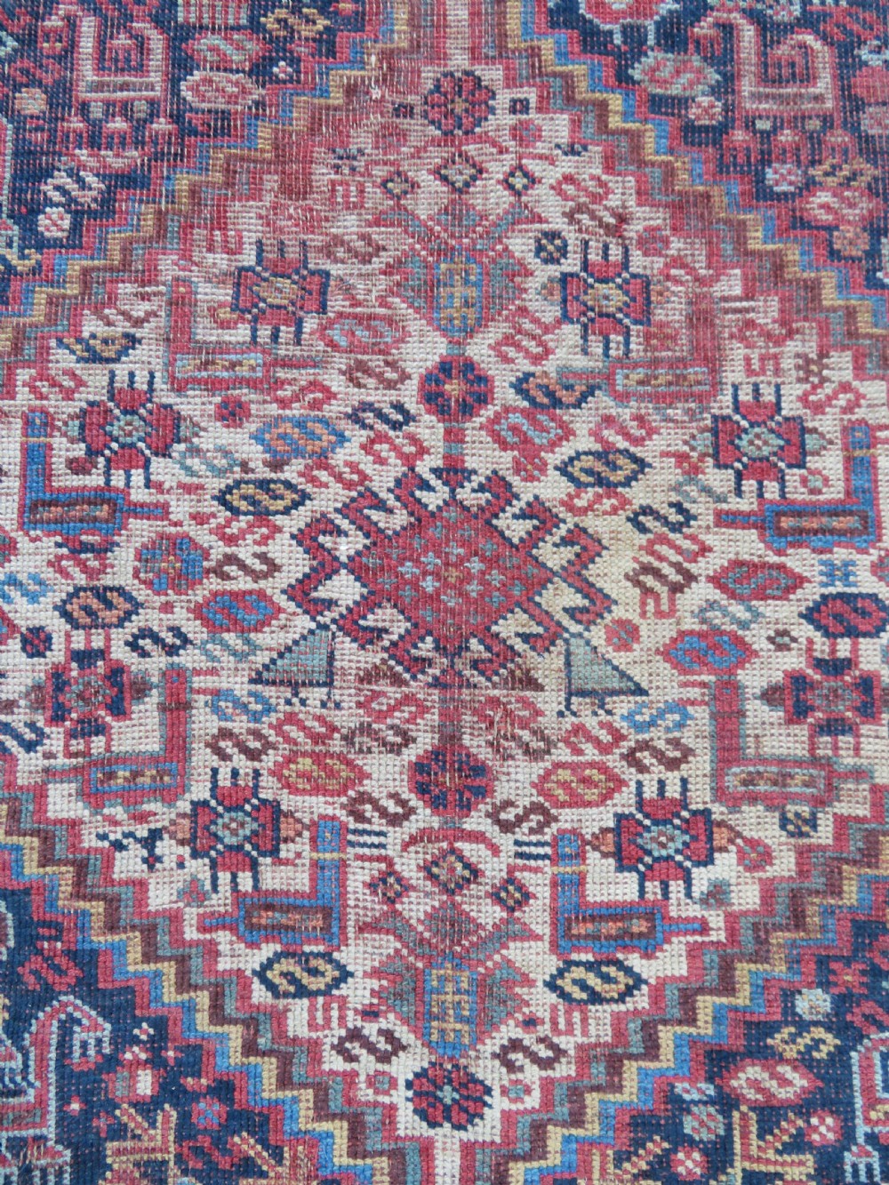 An antique Khamseh nomadic wool rug featuring complex geometric medallions, bird motifs, and multi-layered borders in terracotta, navy blue, and cream. View III