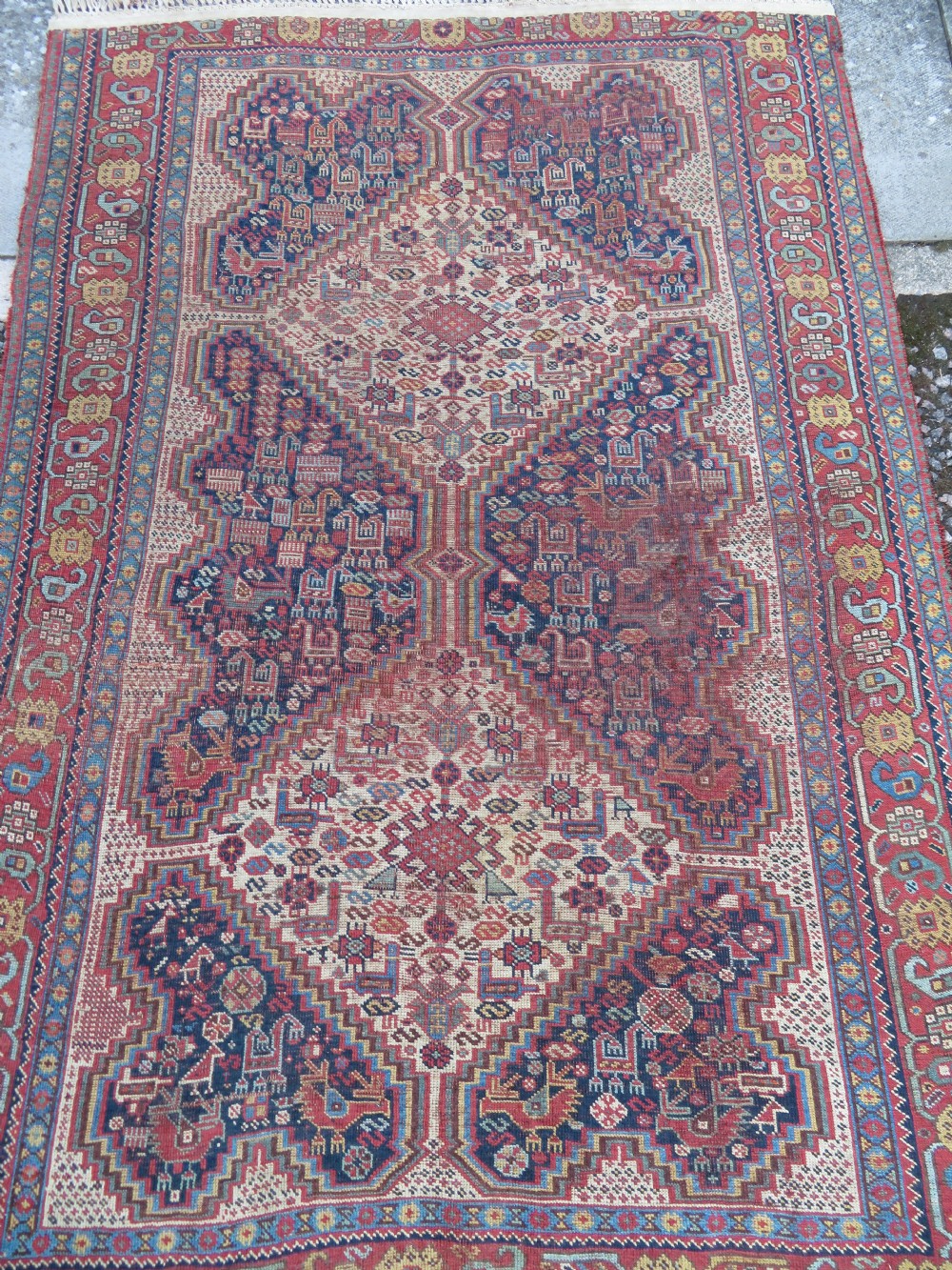 An antique Khamseh nomadic wool rug featuring complex geometric medallions, bird motifs, and multi-layered borders in terracotta, navy blue, and cream. View IV